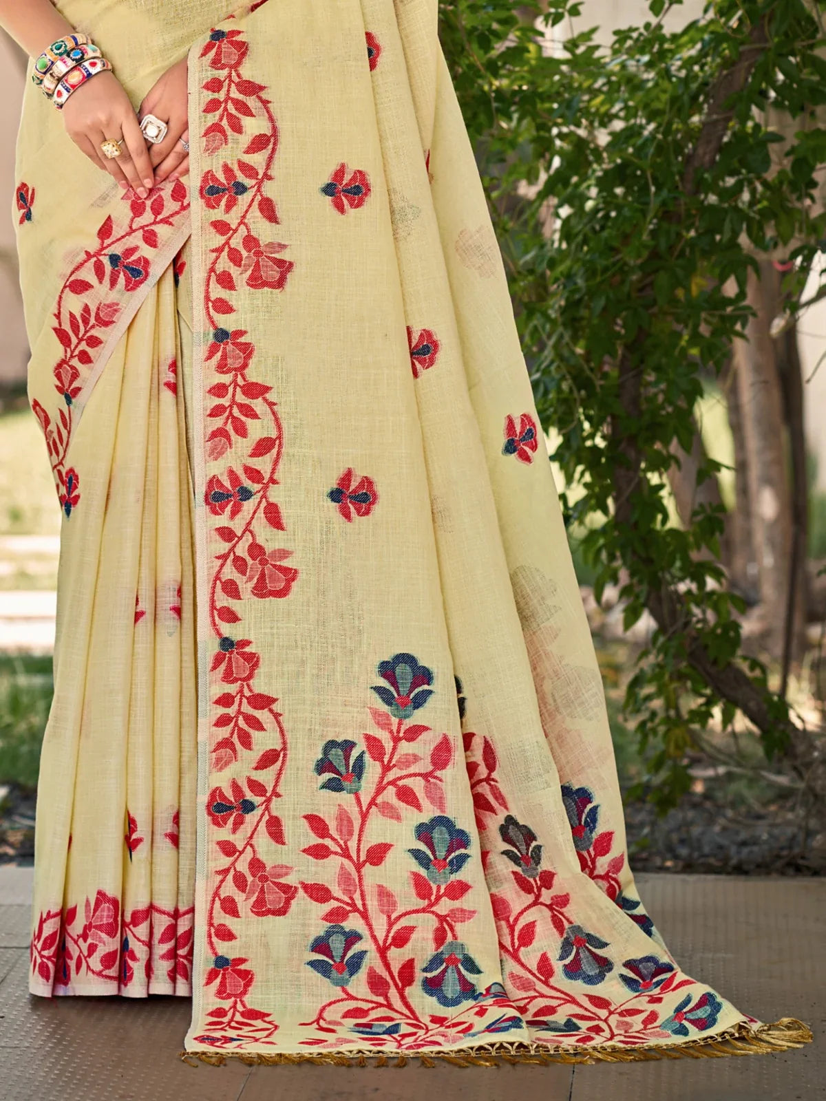 Closeup of Tarani Lilen light yellow saree fabric showing floral embroidery details