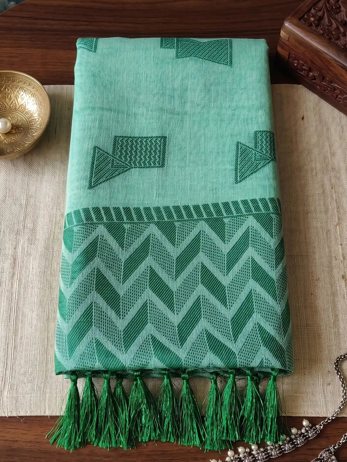 Tarani folded mint green linen cotton saree closeup showing geometric woven design border and tassels