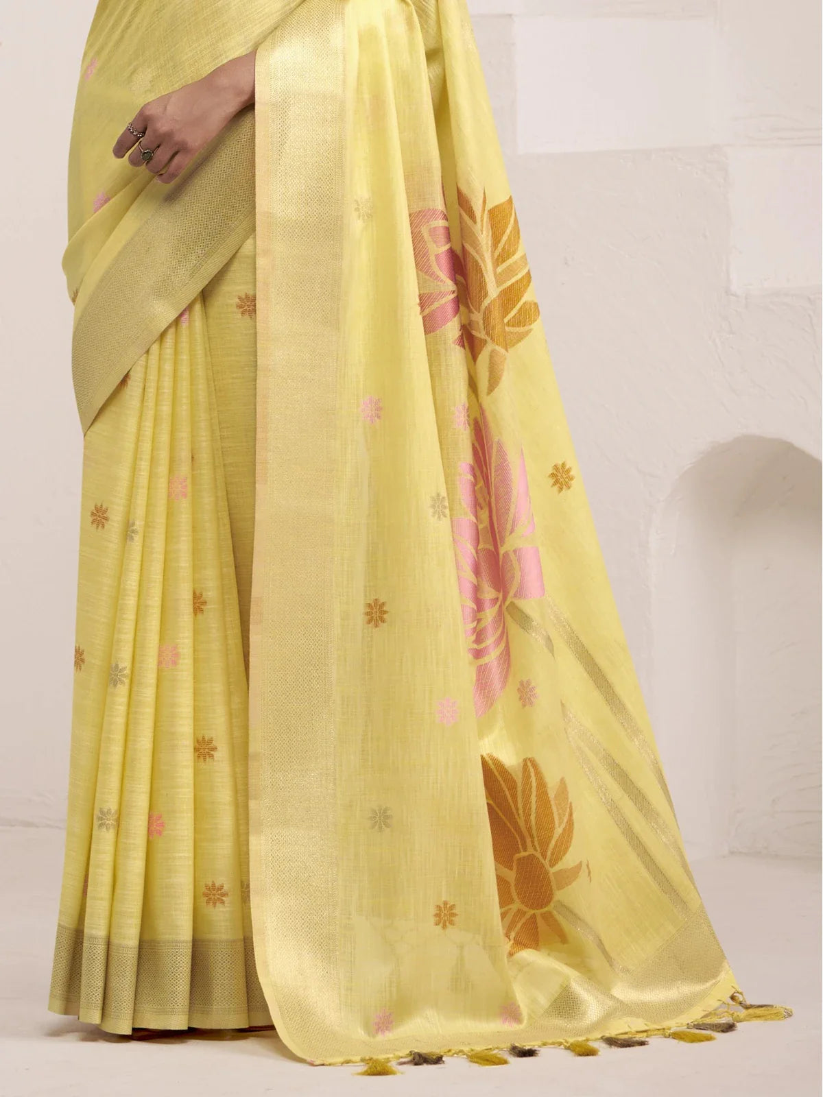 Tarani yellow linen saree pallu view highlighting floral jacquard design and woven tassels