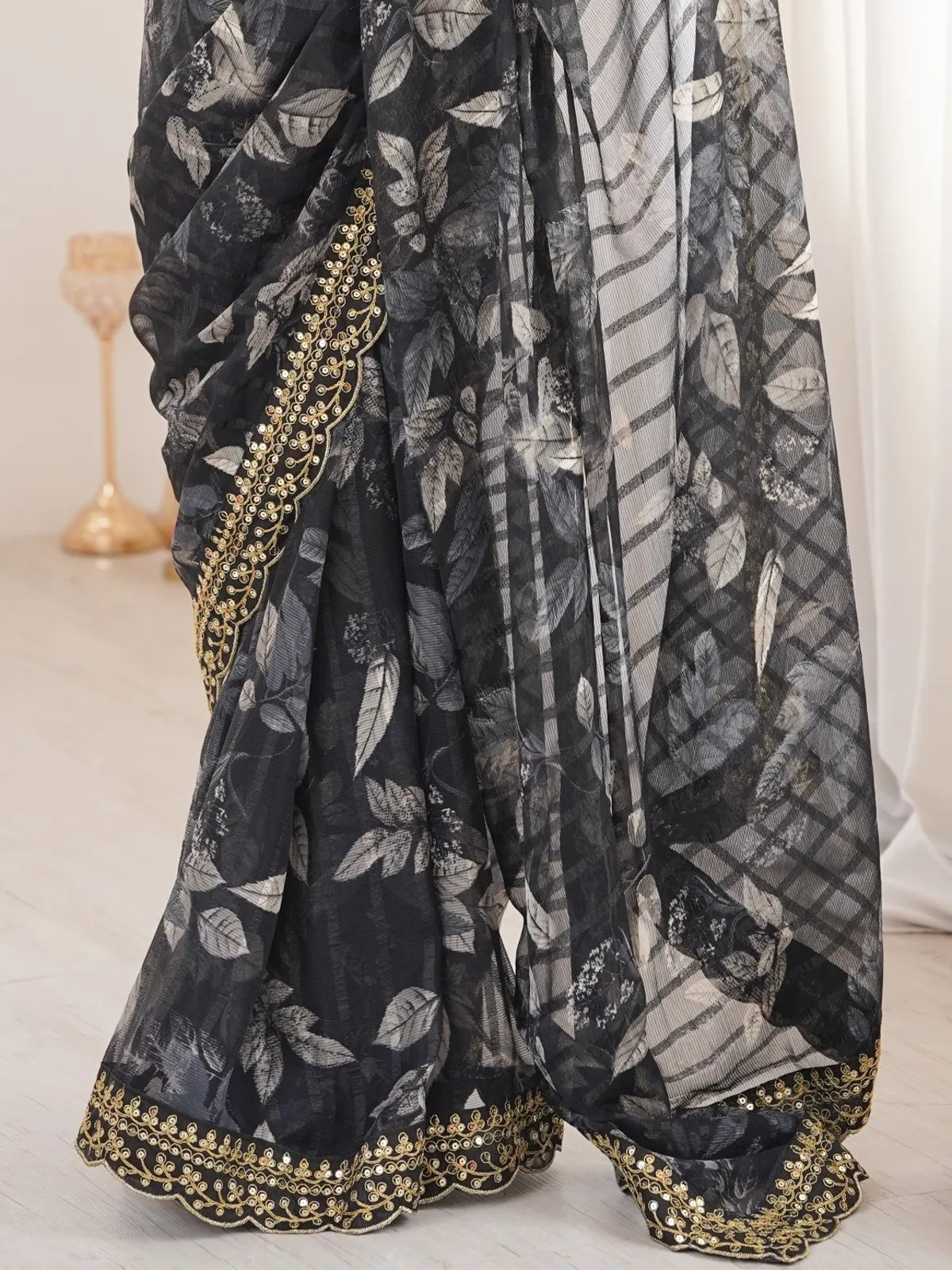 Tarani black saree closeup with golden border and floral marble chiffon texture