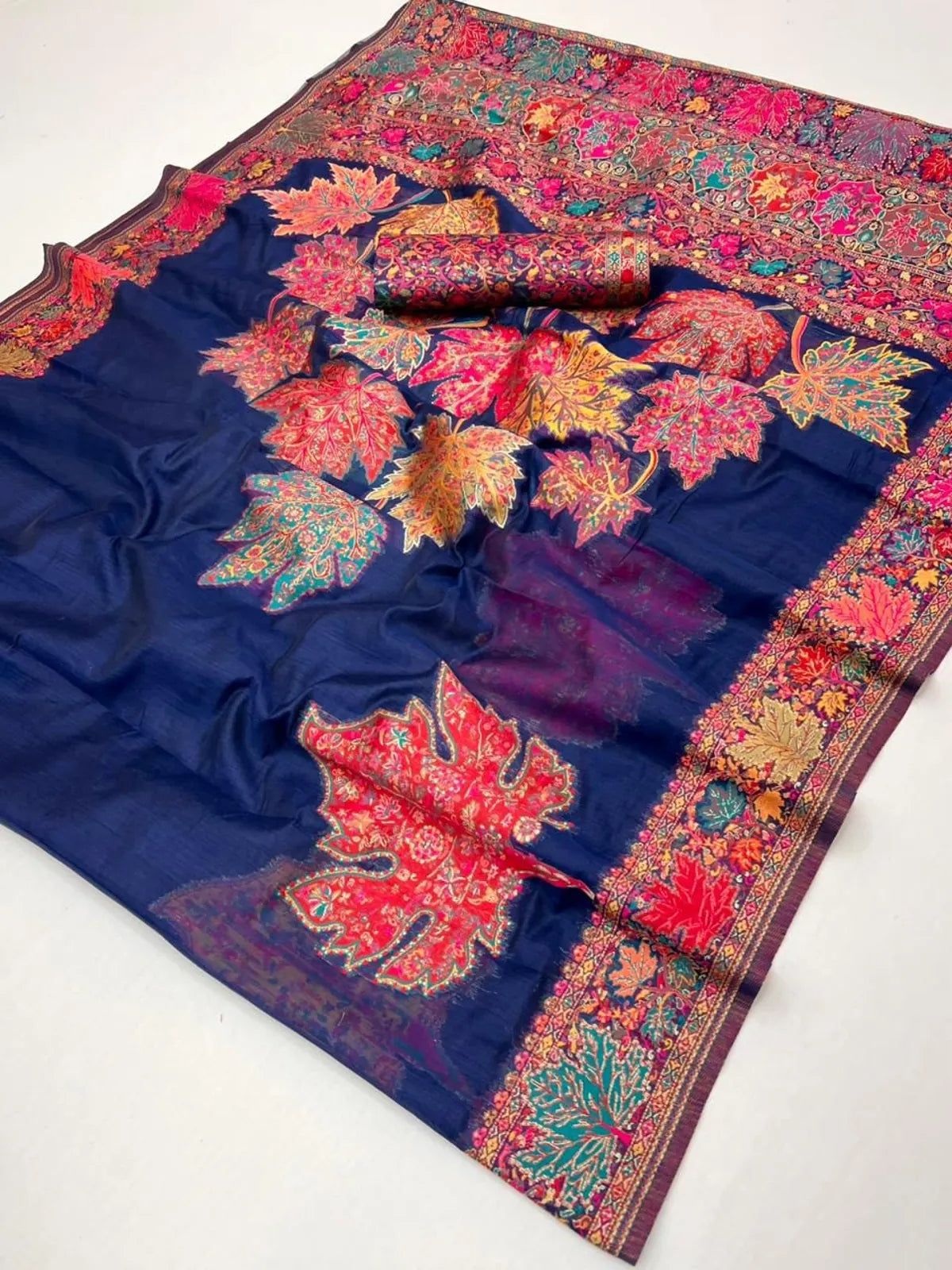 Tarani pallu section with vibrant woven detailing in red, teal and orange hues, laid flat showing blouse roll, pallu view