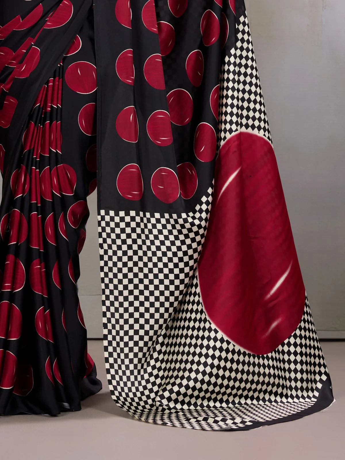 Tarani close-up of bold circular red print on soft black modal satin saree fabric