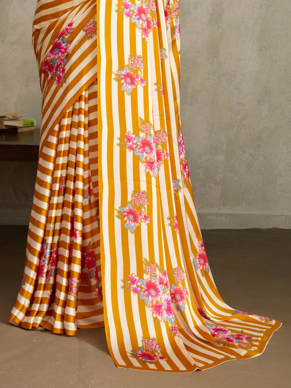 Tarani saree closeup showing satin texture, mustard white stripes and bright floral detailing