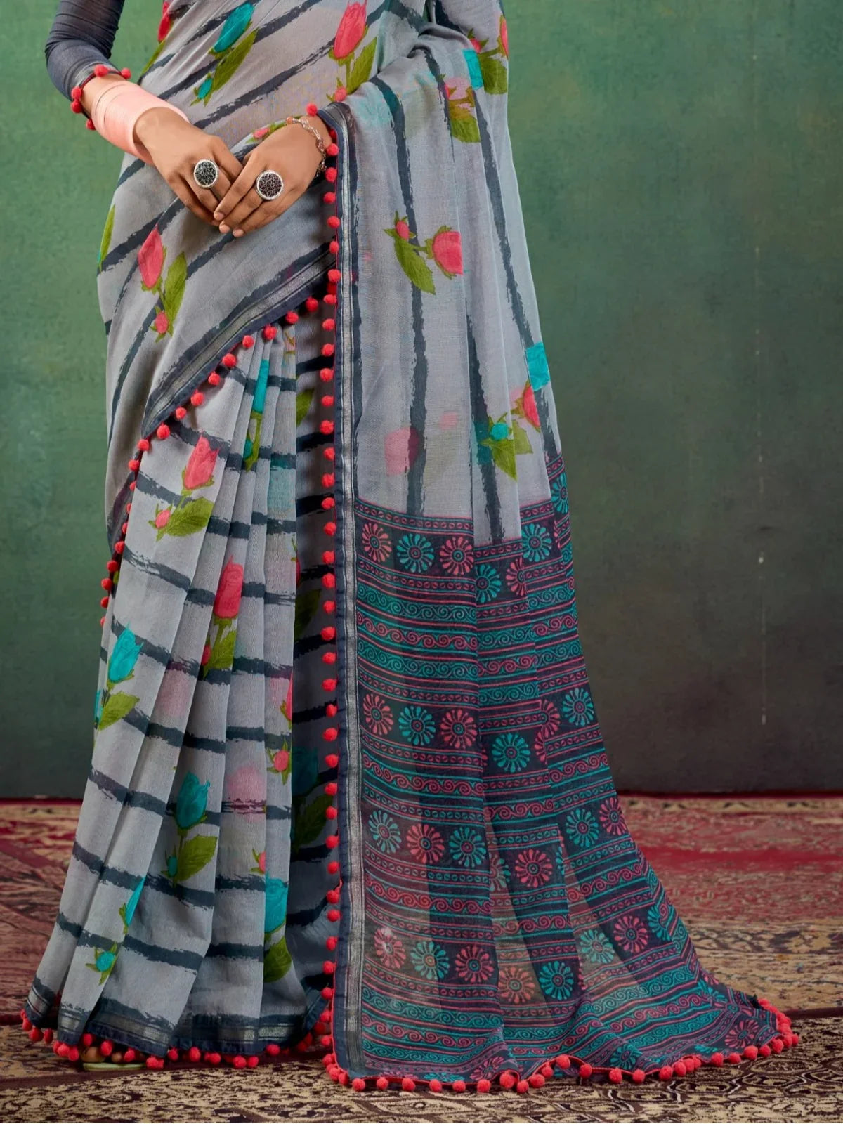 Tarani grey mul mul cotton saree pallu view with intricate blue and red geometric design and pom pom border