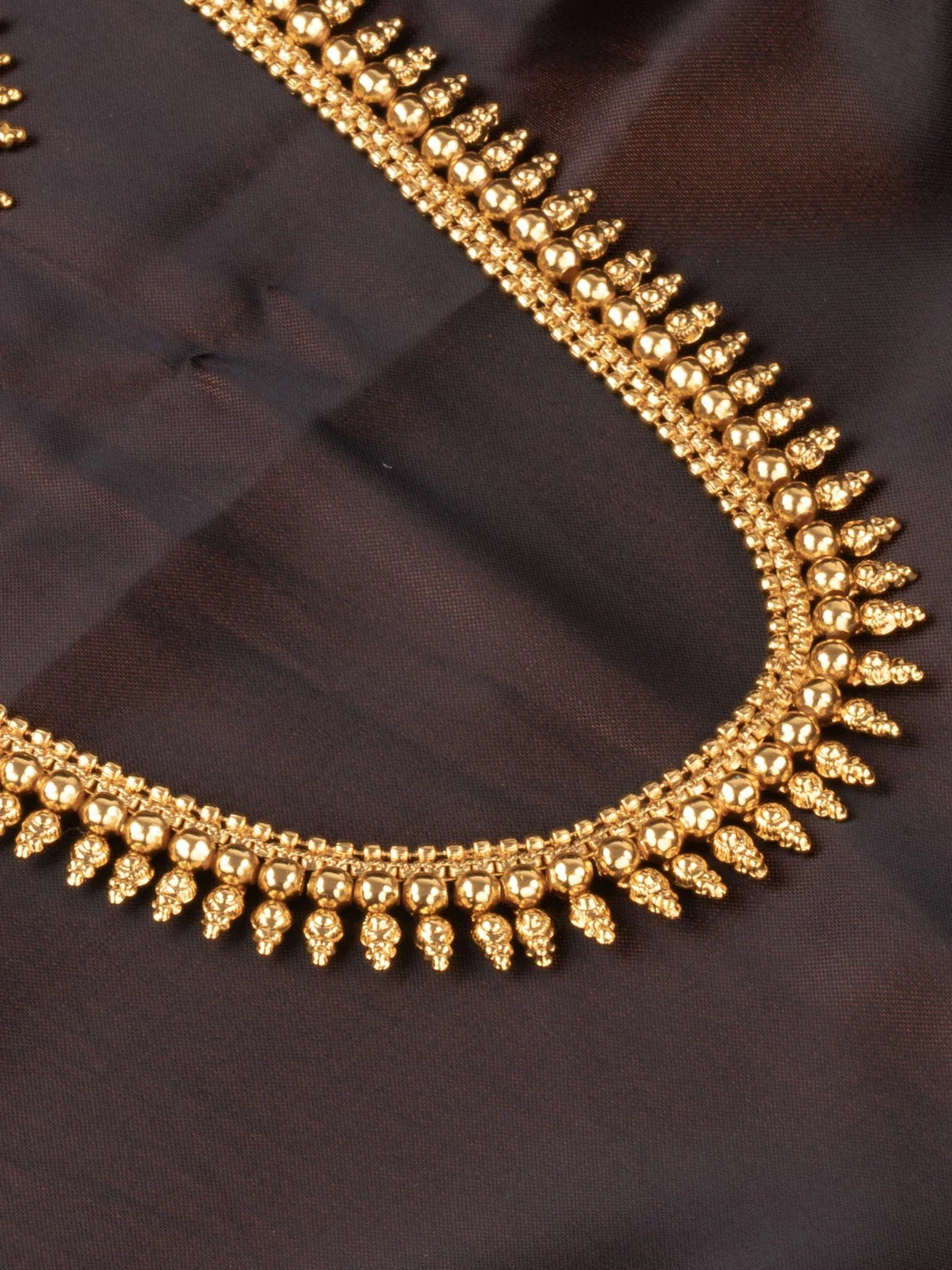 Tarani closeup view of gold plated necklace showing antique detailing for weddings