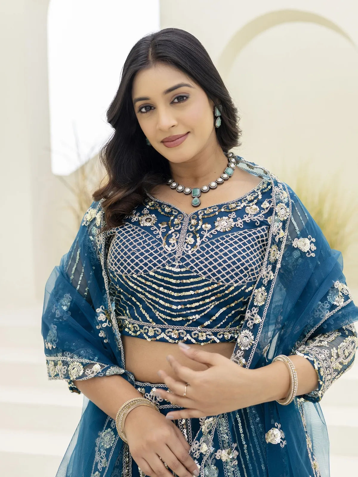 Tarani blue net lehenga showing close-up of embroidered blouse with transparent dupatta in upper body pose