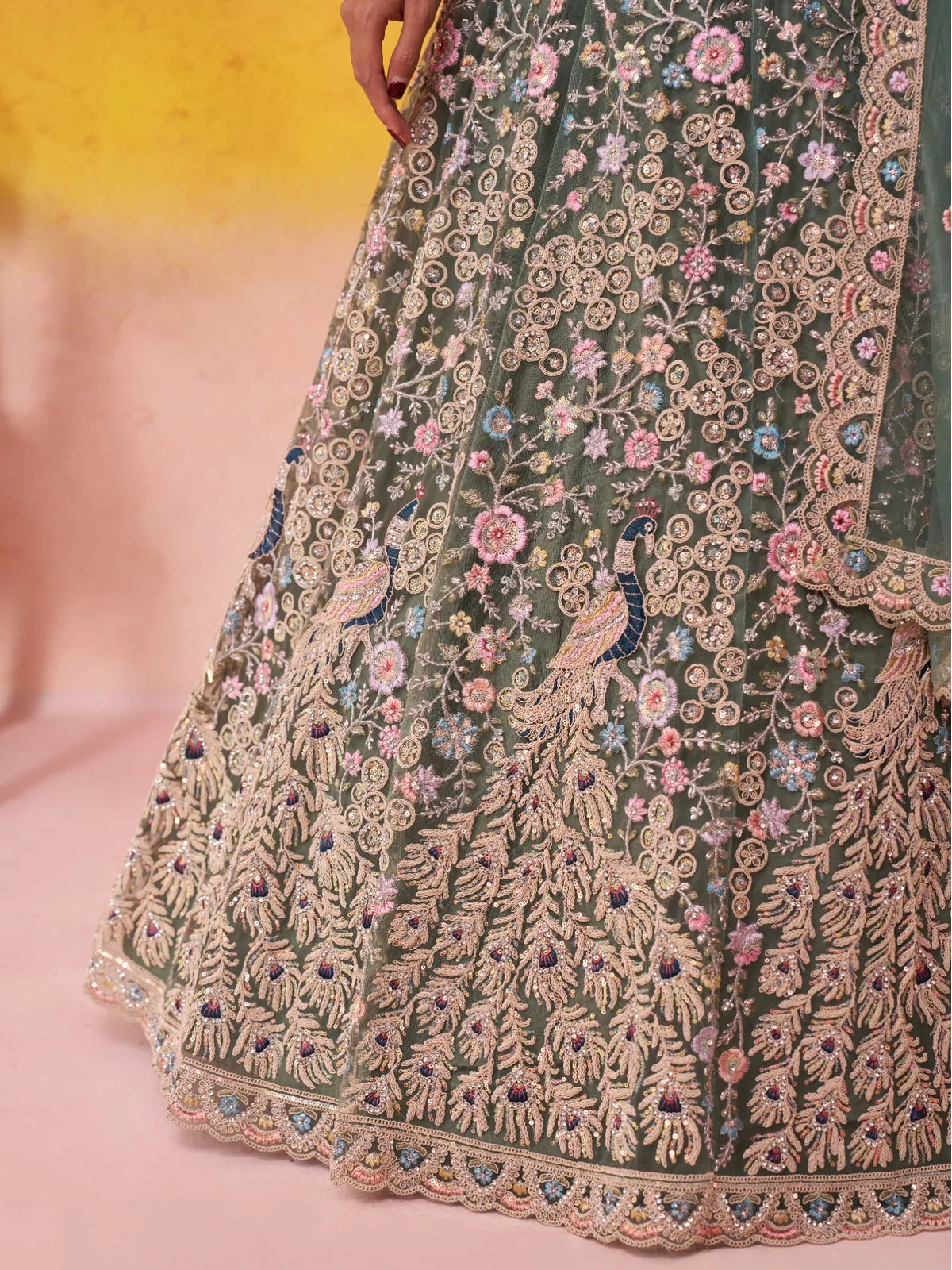 Closeup showing peacock embroidery and floral details on Tarani green net lehenga