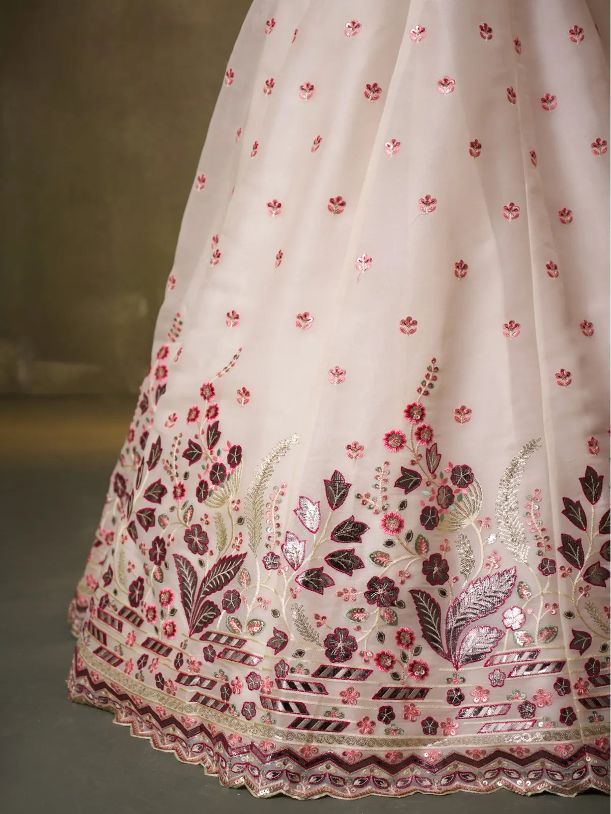 Closeup of Tarani lehenga border with intricate pink floral embroidery and gota work