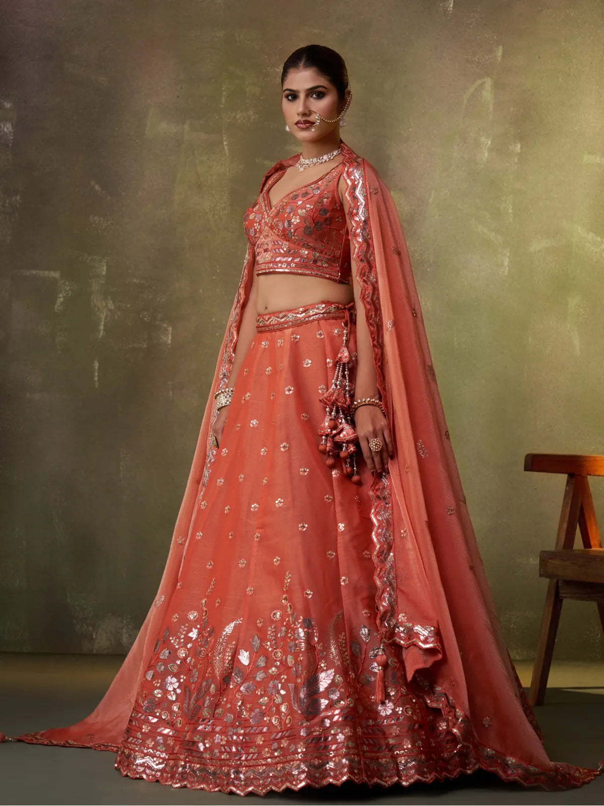 Tarani orange lehenga side pose showcasing handcrafted latkans, sequins work and ethnic elegance