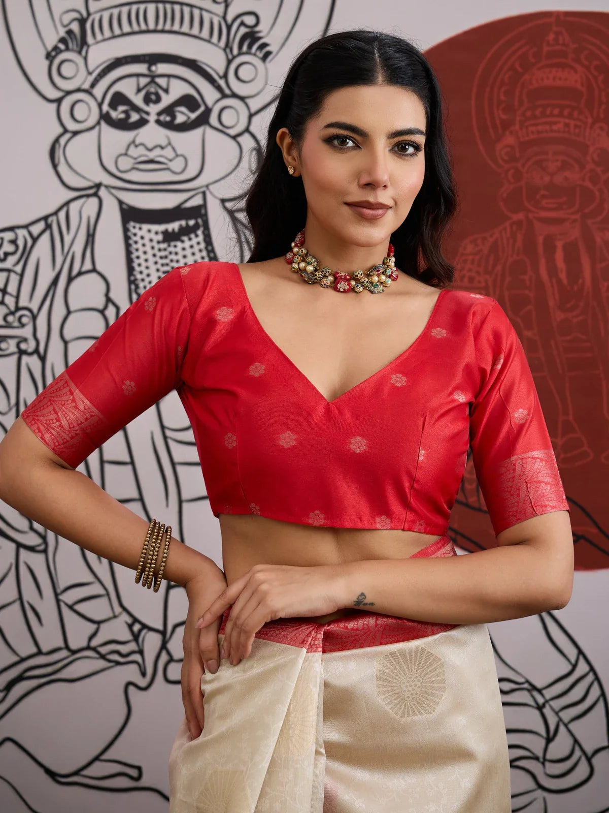 Tarani beige paper silk saree styled with red blouse captured in upper body pose for detailing