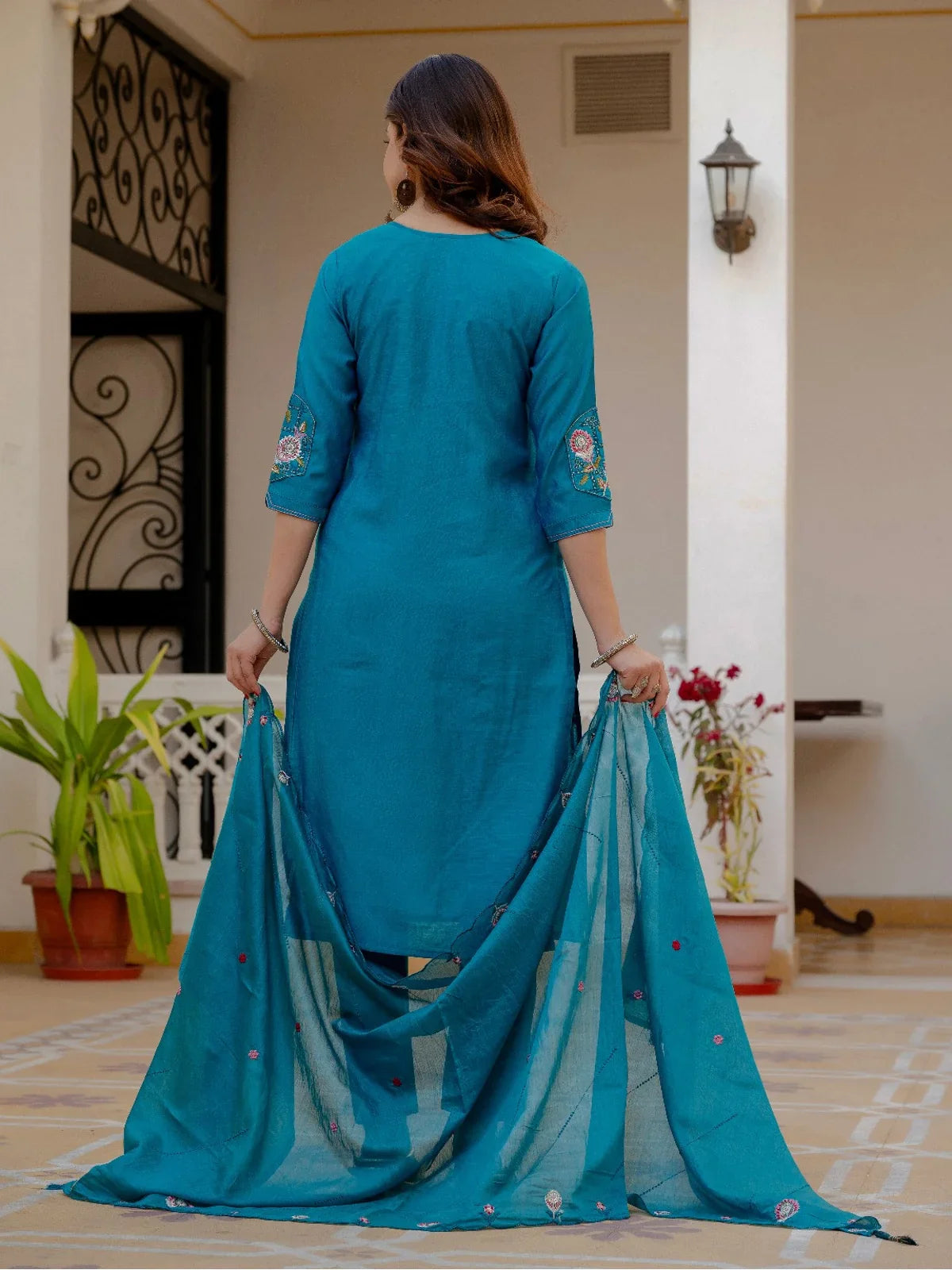 Tarani back view of teal embroidered dress with maslin silk dupatta held gracefully