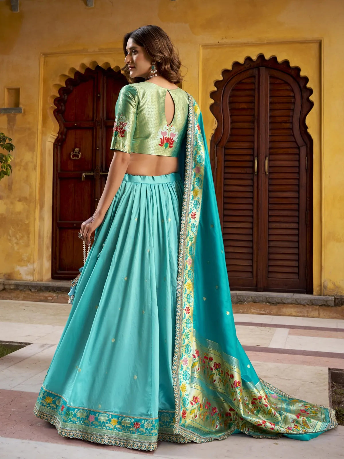 Back view of Tarani stitched blouse with embroidery and flared lehenga in green silk
