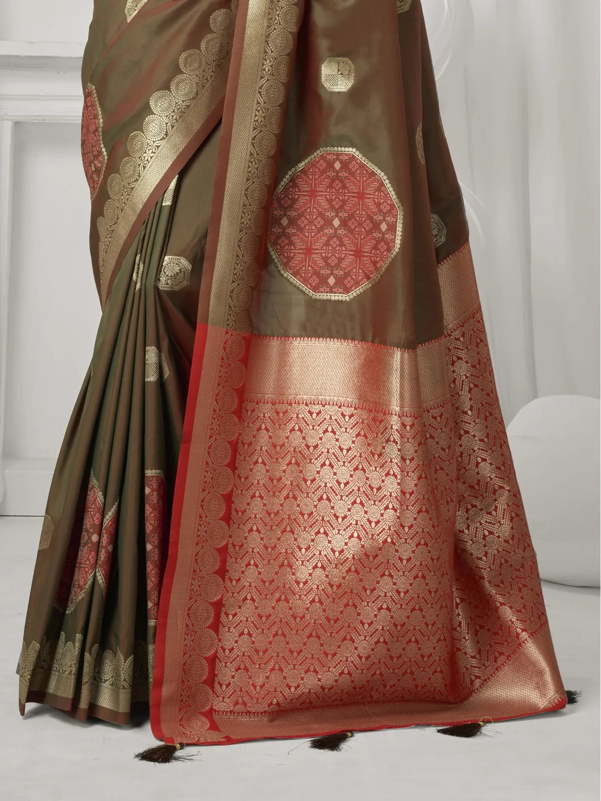 Tarani brown silk saree close pallu view showing golden zari and red pattern with pompom finish