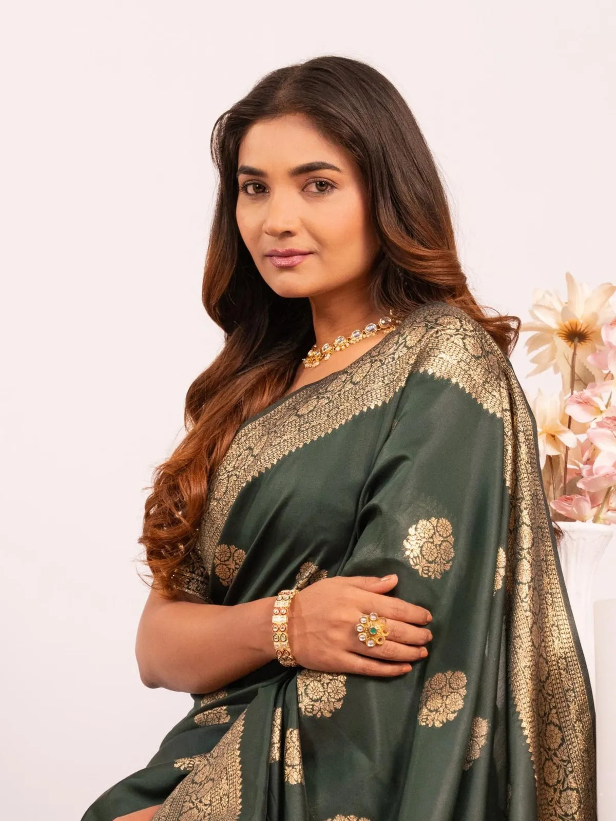 Tarani premium green banarasi saree showing golden border and model upper body pose