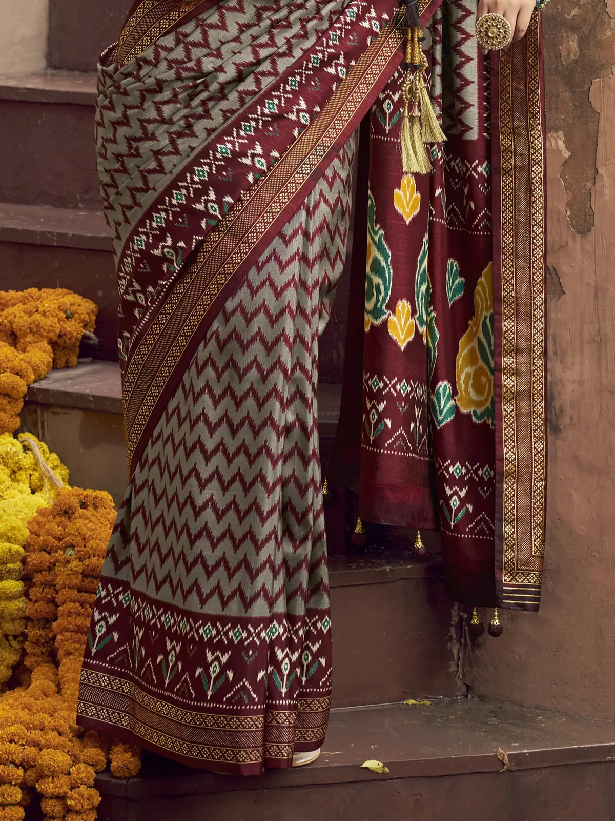 Tarani maroon silk patola saree pallu close-up with tassels and floral detailing
