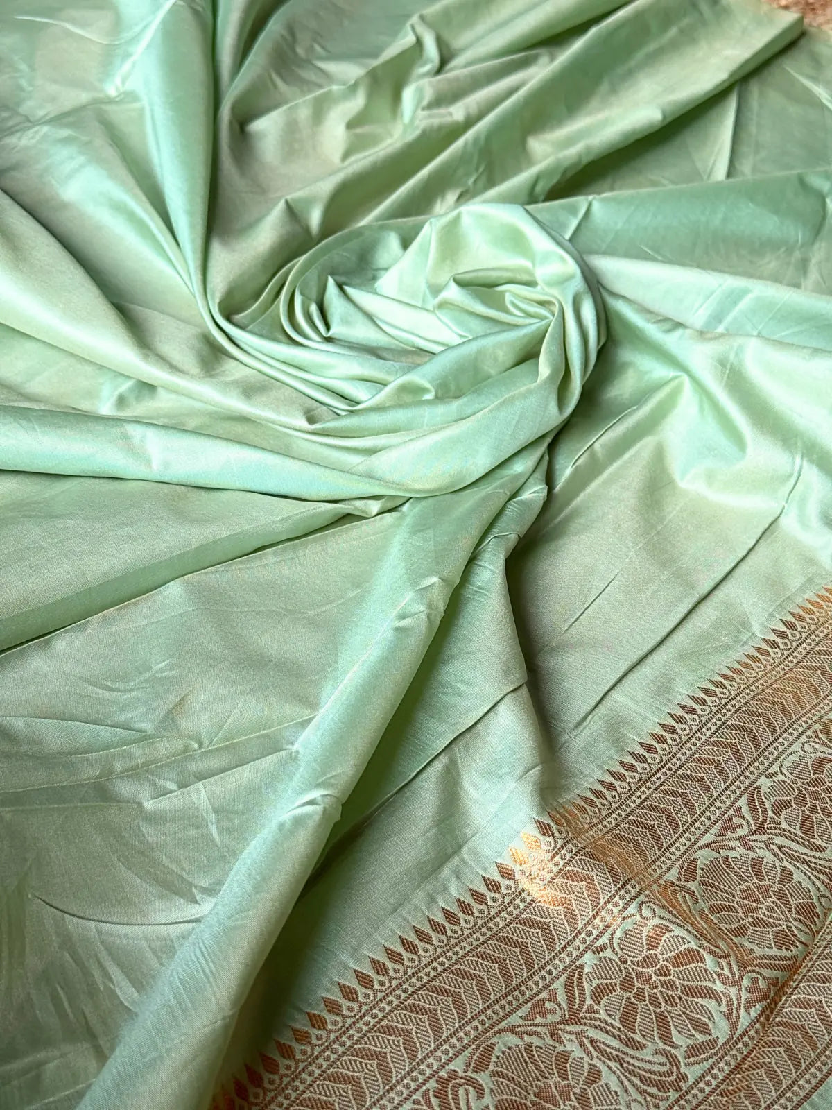 Tarani closeup view of green silk saree fabric with floral motifs and zari design