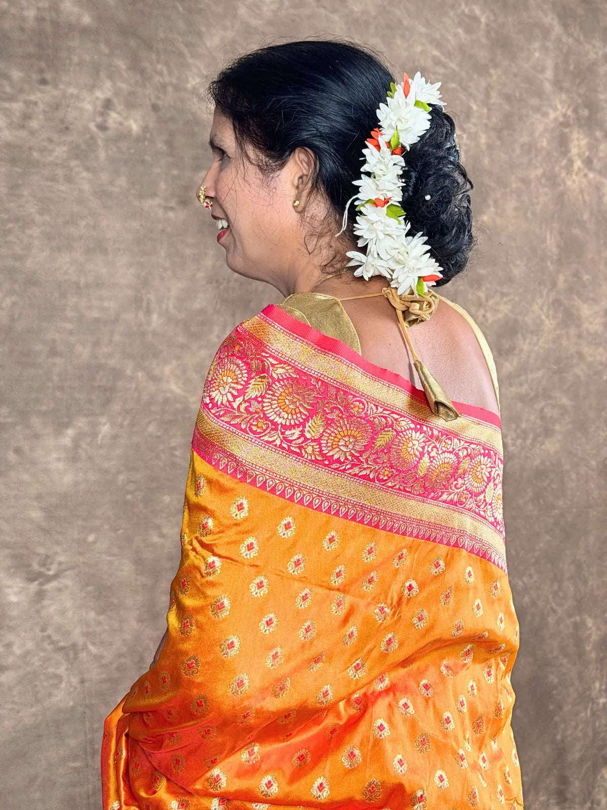 Tarani premium orange silk saree blouse view with detailed back design and zari border