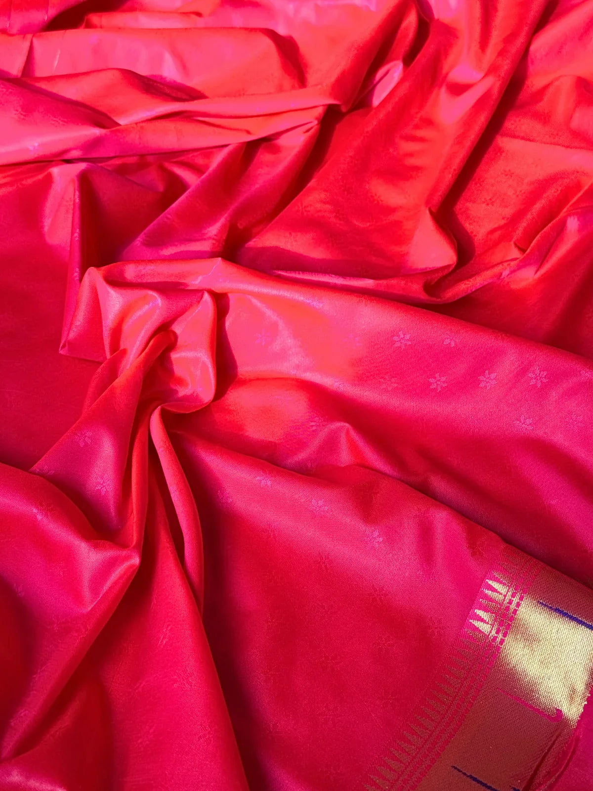Tarani closeup of orange silk saree fabric with pink zari border and detailing