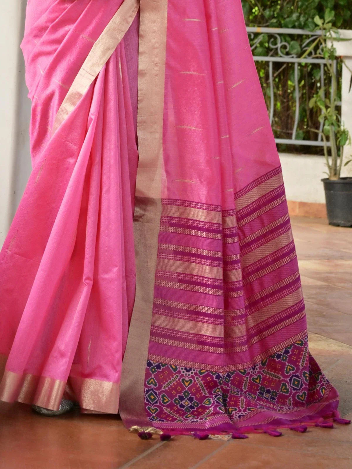 Tarani pink silk saree pallu with golden zari stripes and vibrant tassels captured in traditional back pose