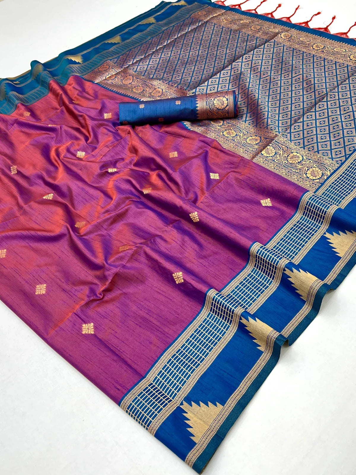 Close-up view of Tarani silk saree fabric showing purple body and detailed golden motifs