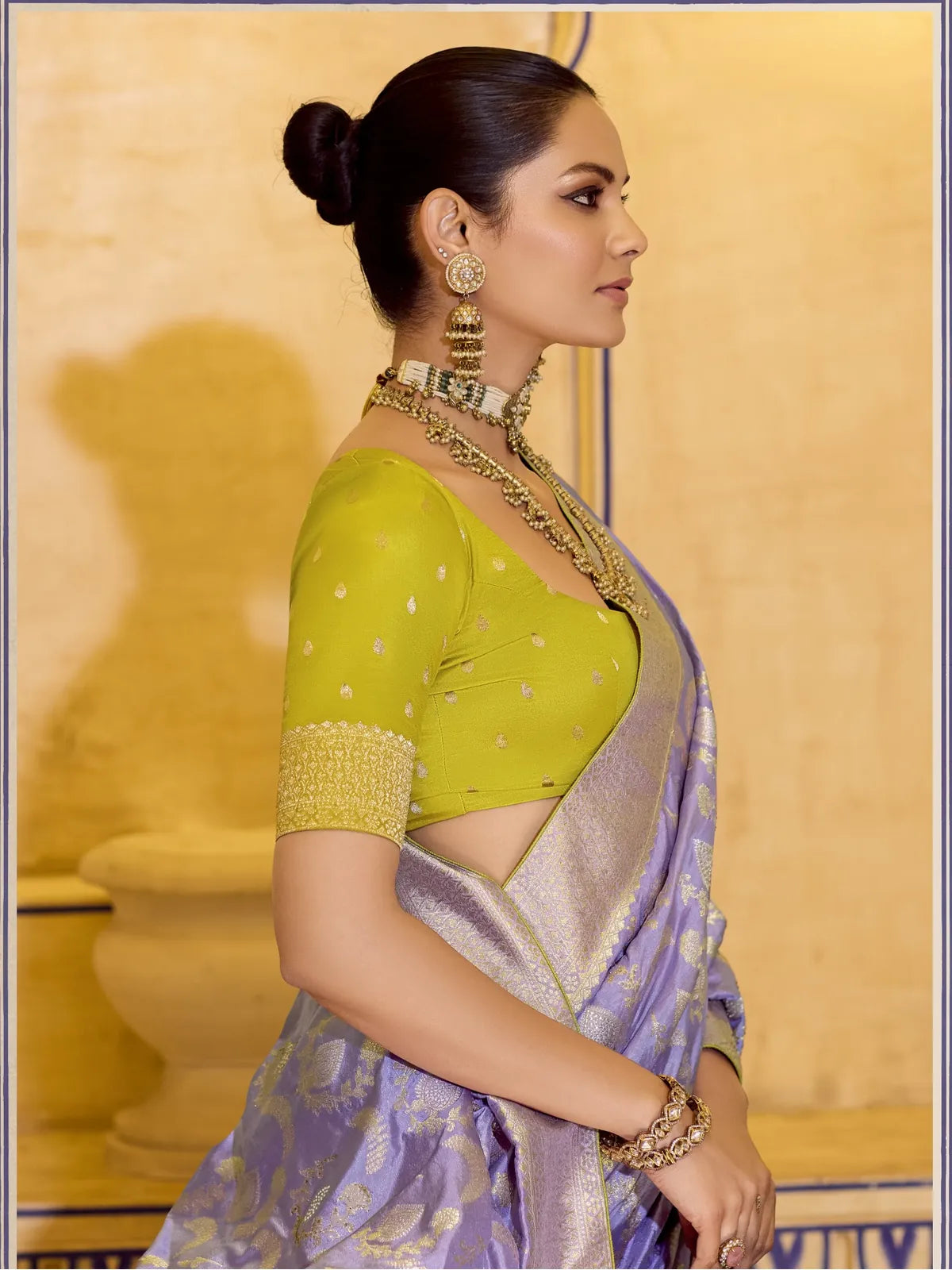 Tarani purple silk saree side pose highlighting contrast green blouse and detailed earrings