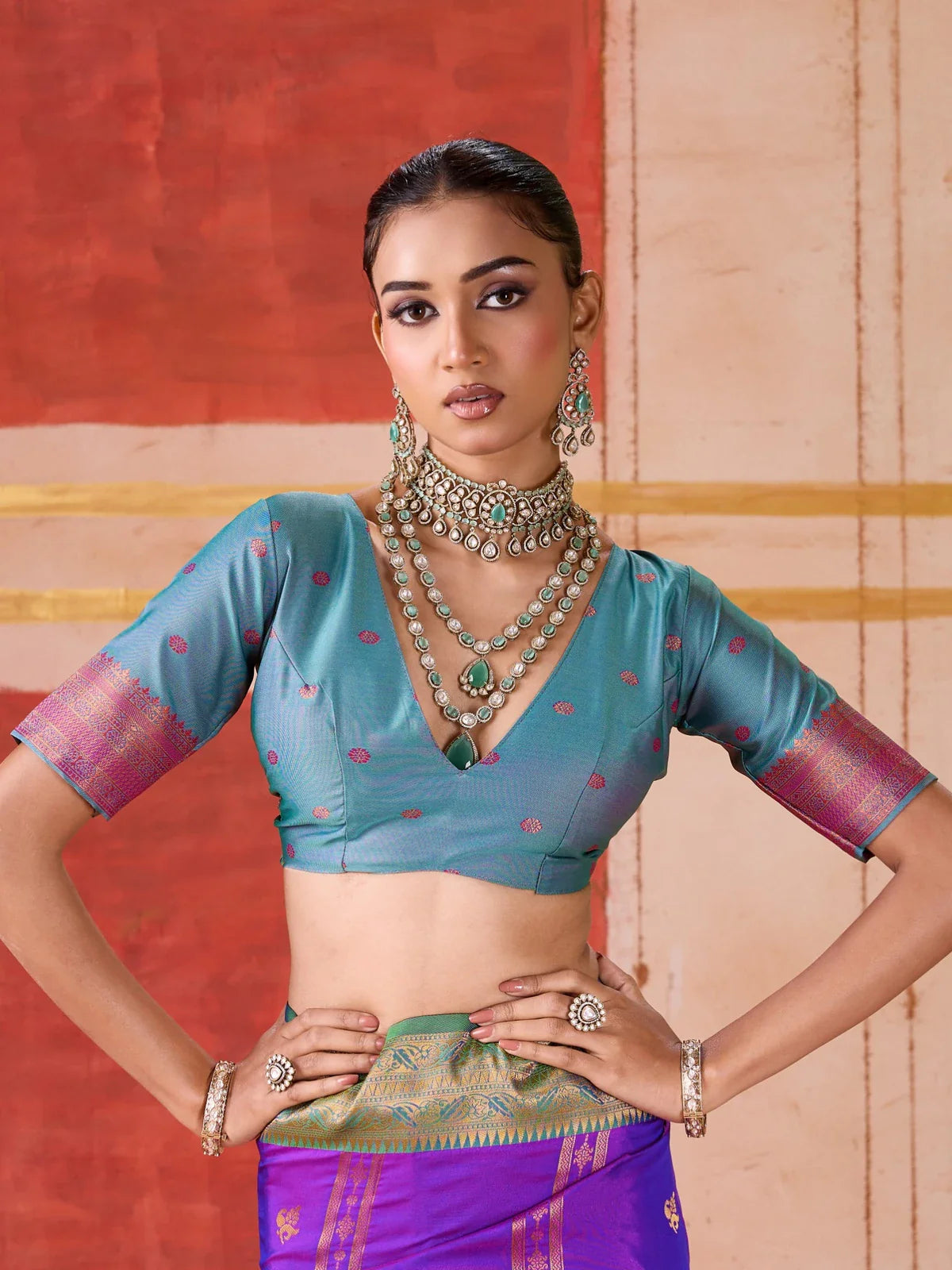 Tarani purple silk saree styled with deep cut sleeve blouse in teal and layered necklace upper body pose