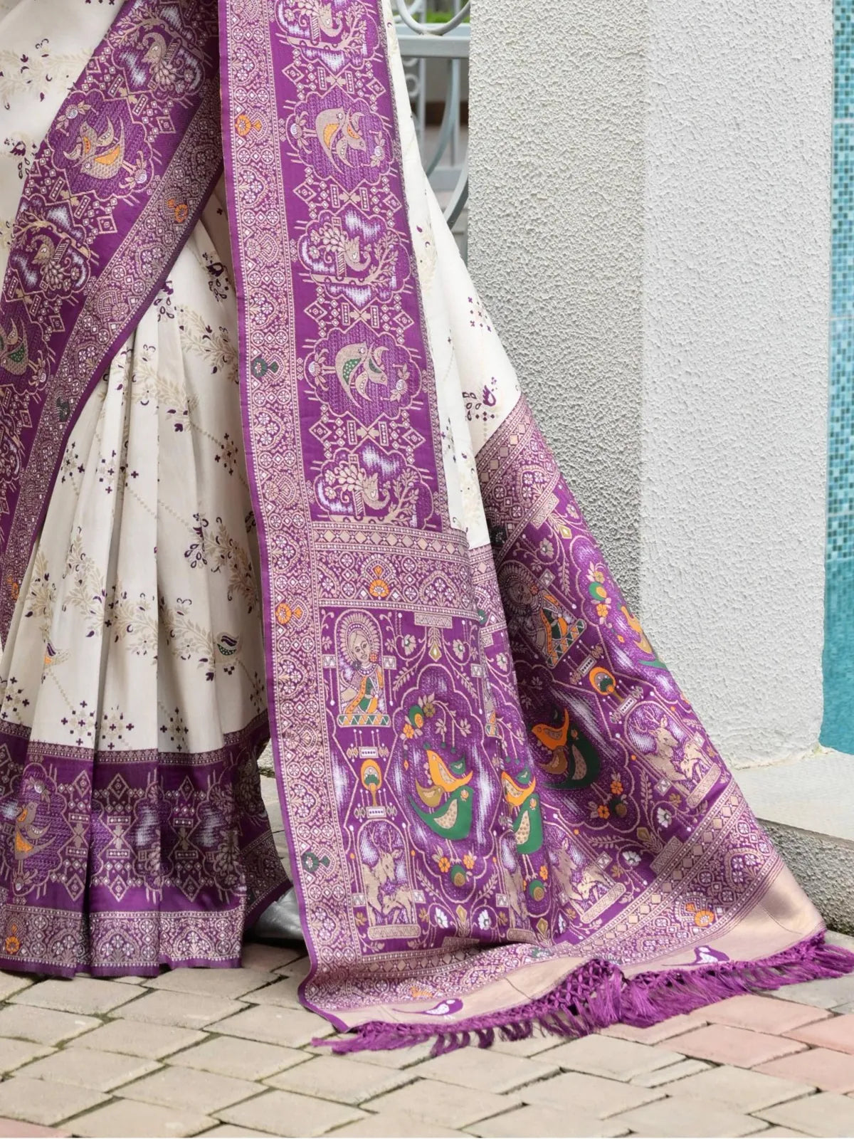 Tarani white saree with intricate purple patola-inspired pallu featuring peacock and deity motifs