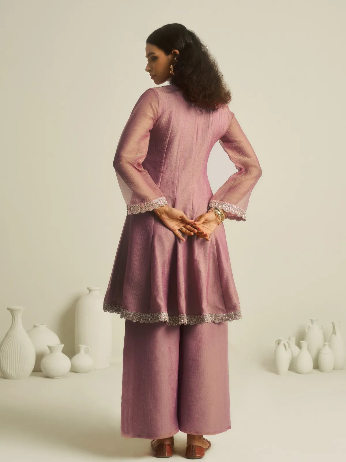 Back view of Tarani lavender dress highlighting long sleeves and flowy back flare