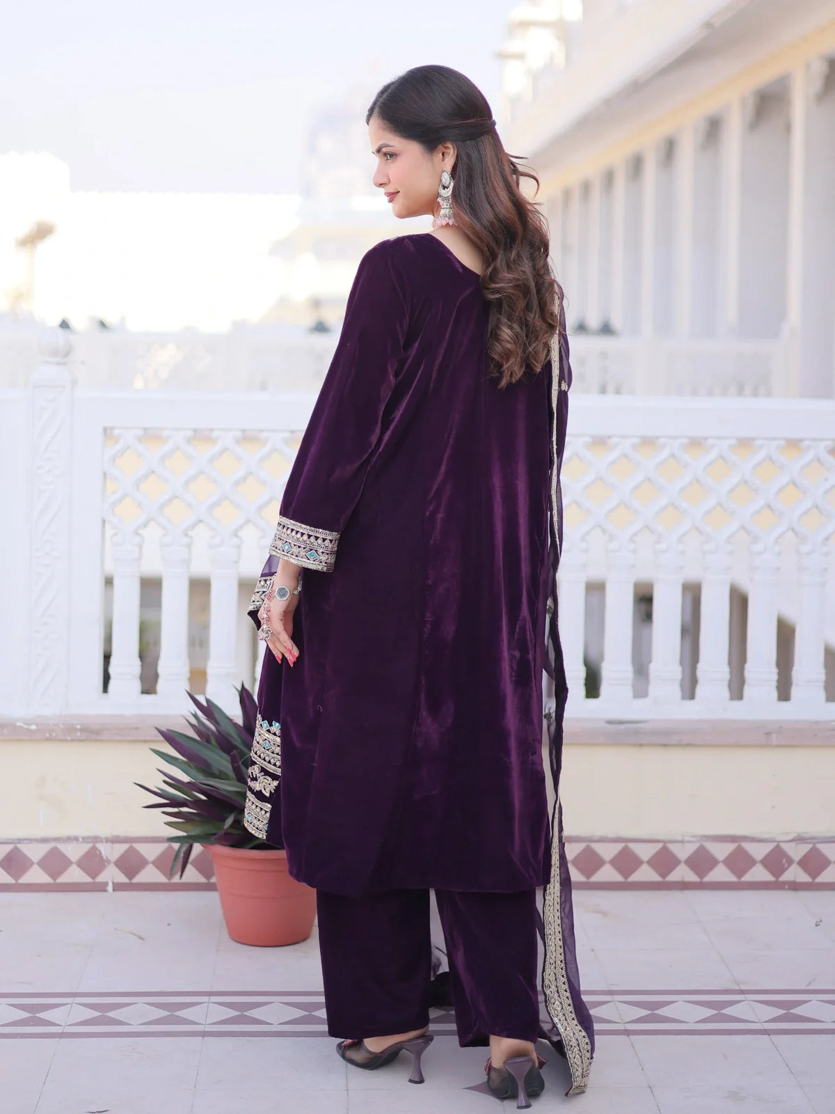 Back pose of Tarani velvet purple dress with embroidery on sleeves and flowing silhouette