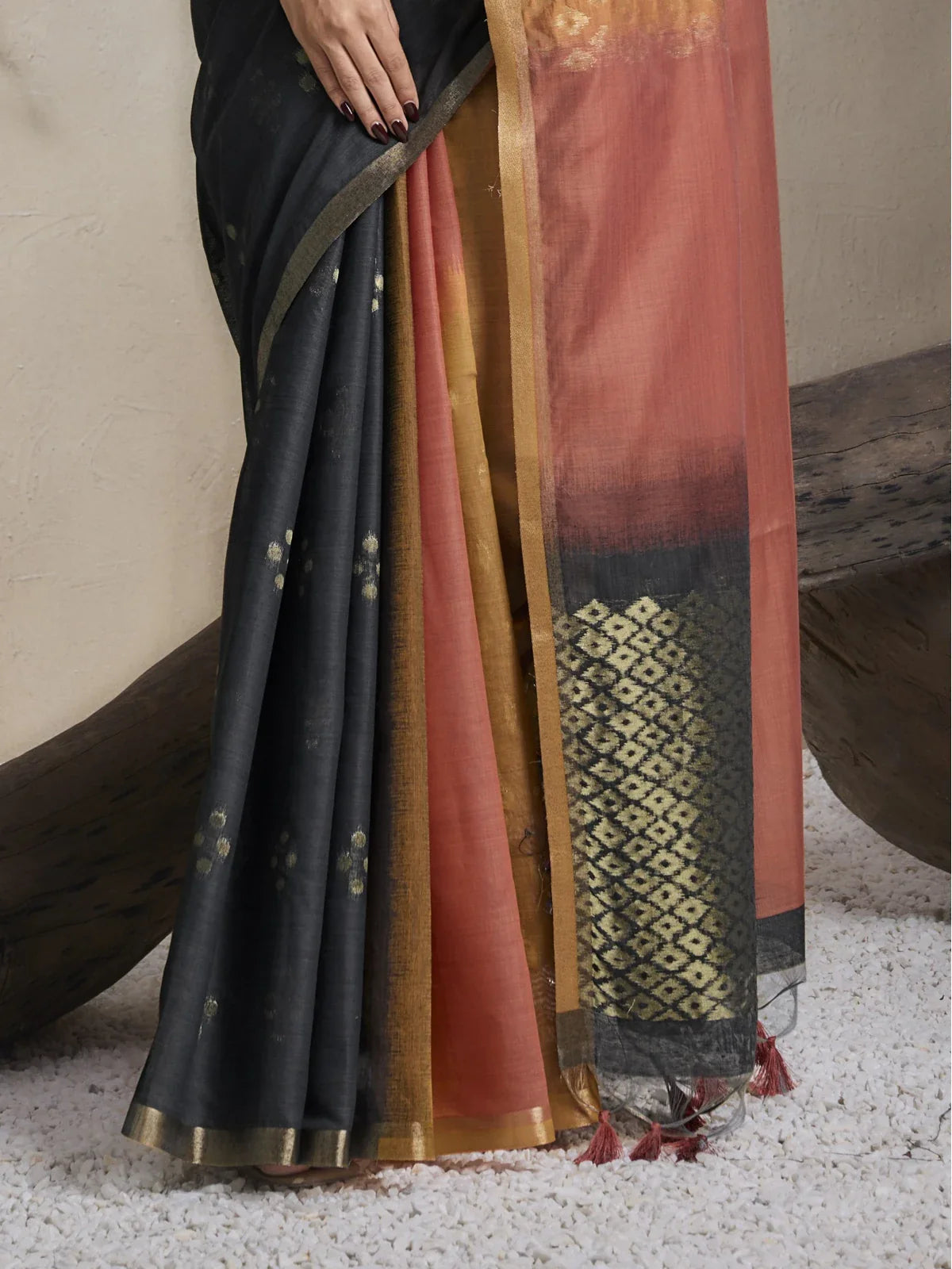 Tarani closeup view of black viscose cotton saree with zari motifs and ochre rust pleats