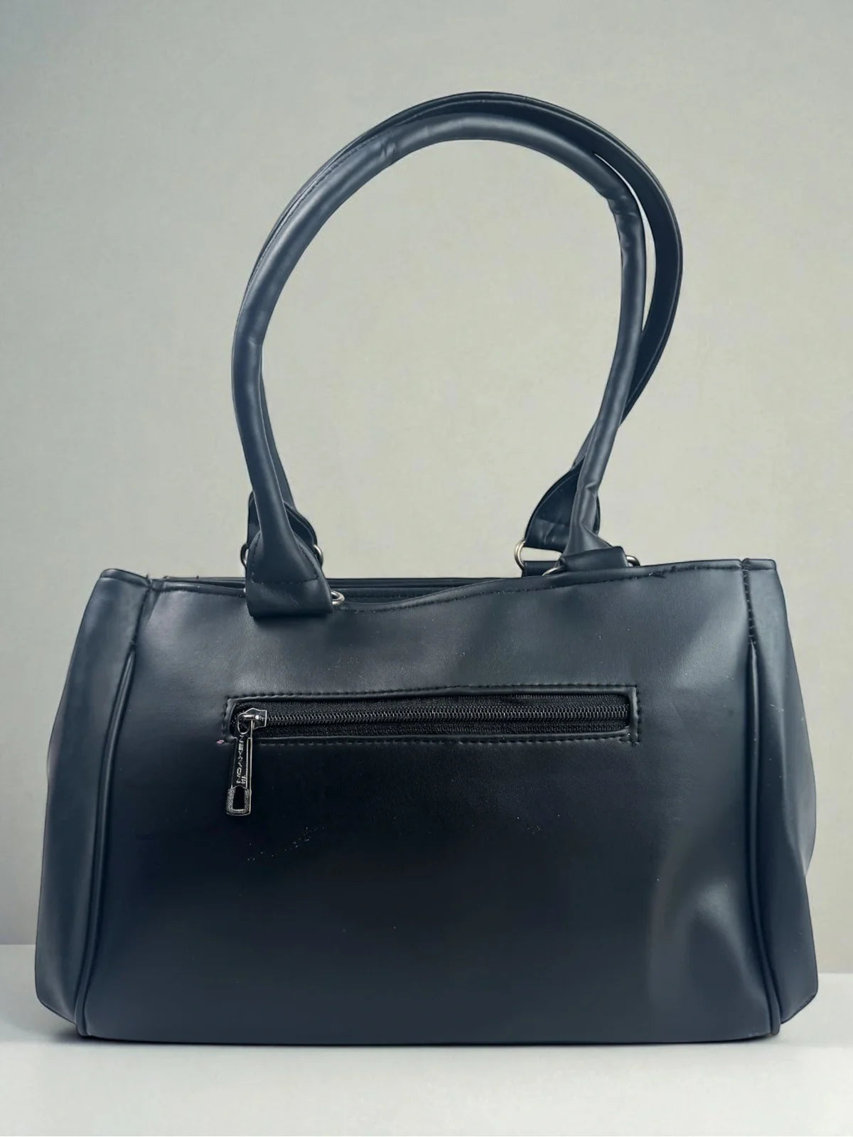 Tarani back view of navy PU leather handbag with zipper compartment